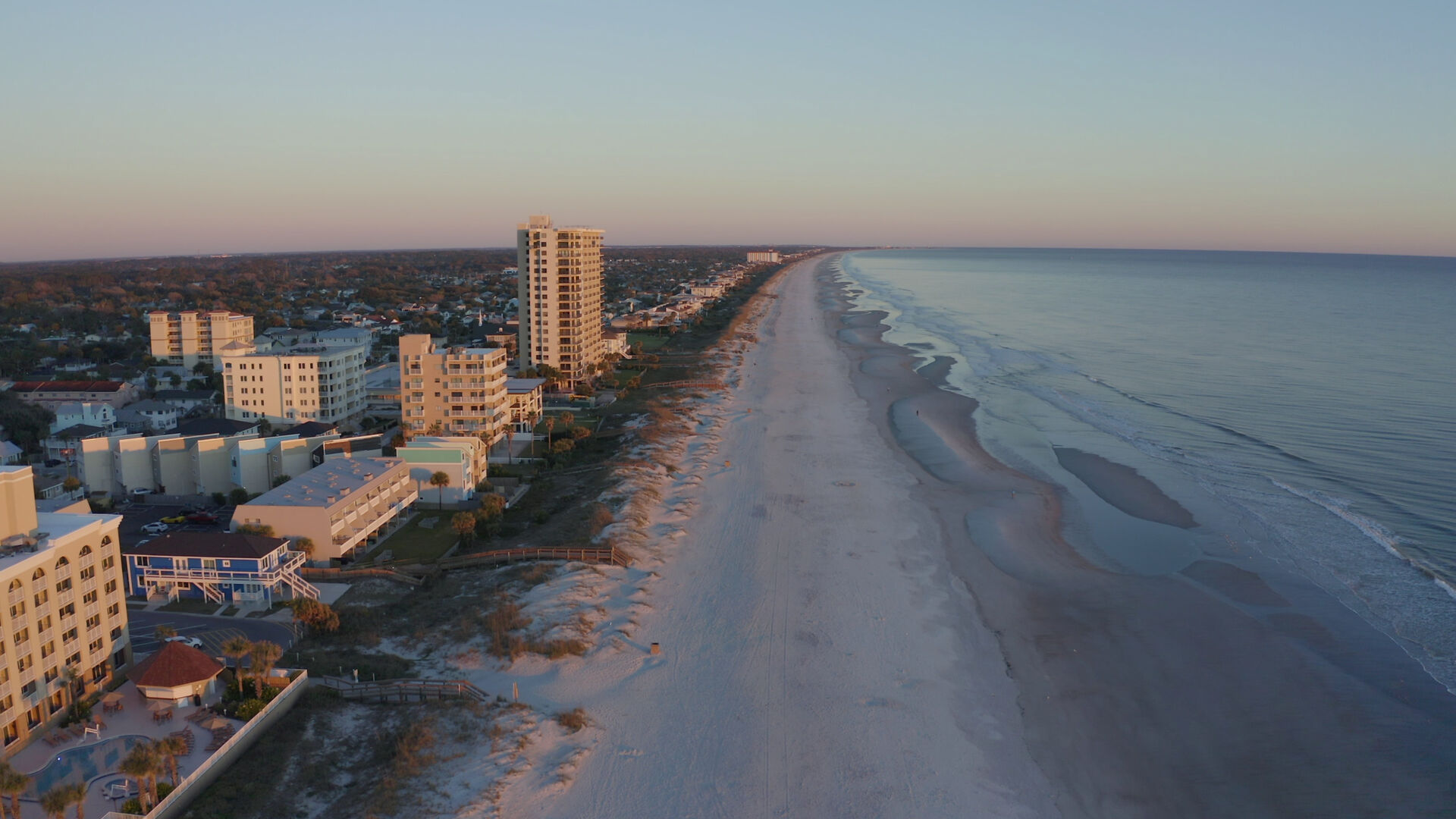 Aerial view of the First Coast coastline at sunset — pristine beaches stretching into the distance